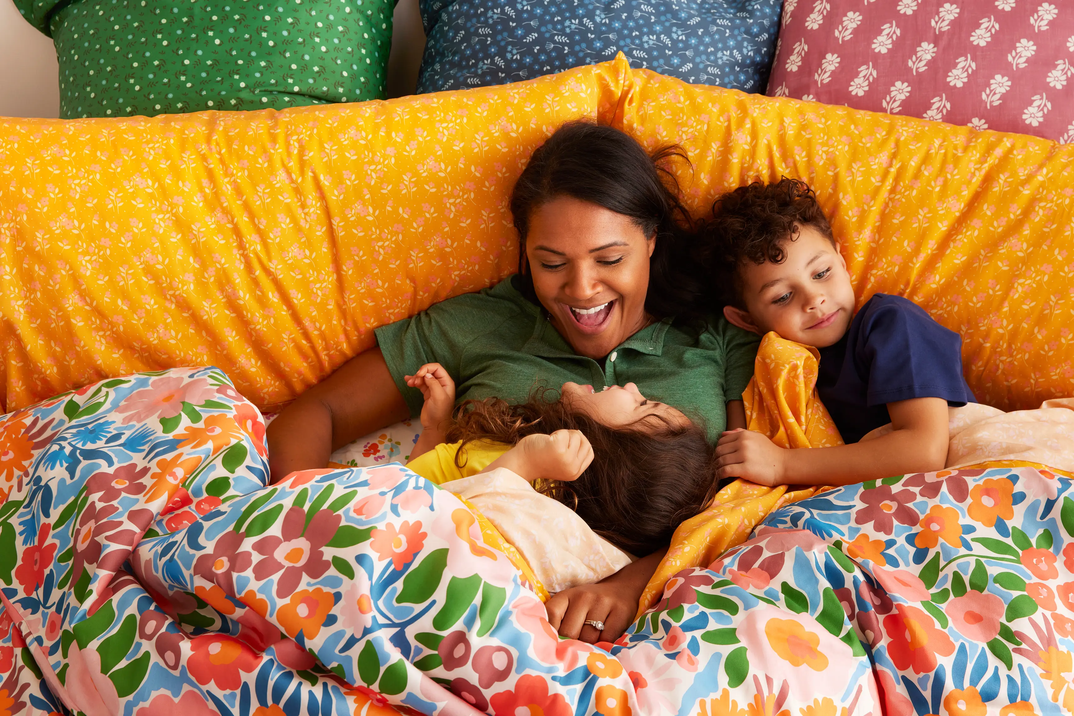 Family snuggling and laughing in colorful Spoonflower bedding.