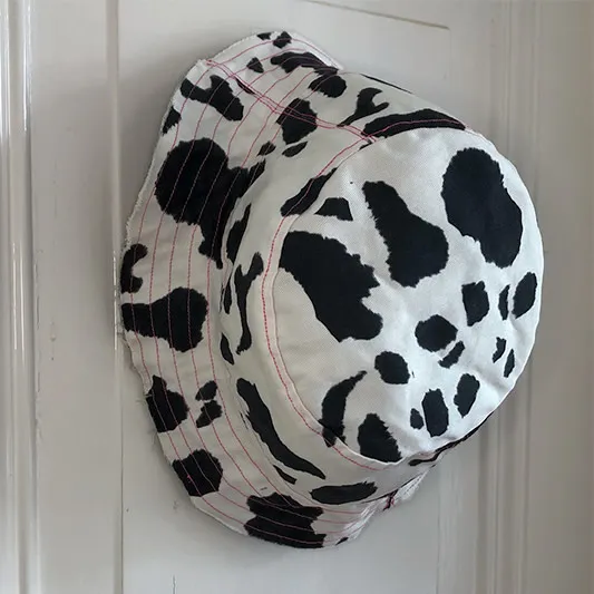 Cow print bucket hat hanging on door