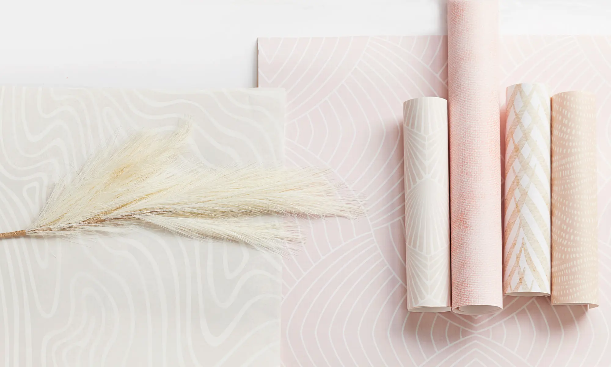 Rolls of light pink wallpaper and a dried grass.