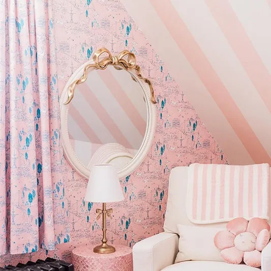 Pink wallpaper and comfy rocking chair in a bedroom.