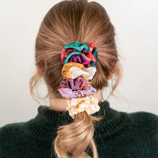 Back of girls head with hair pulled back by multiple colorful scrunchies.
