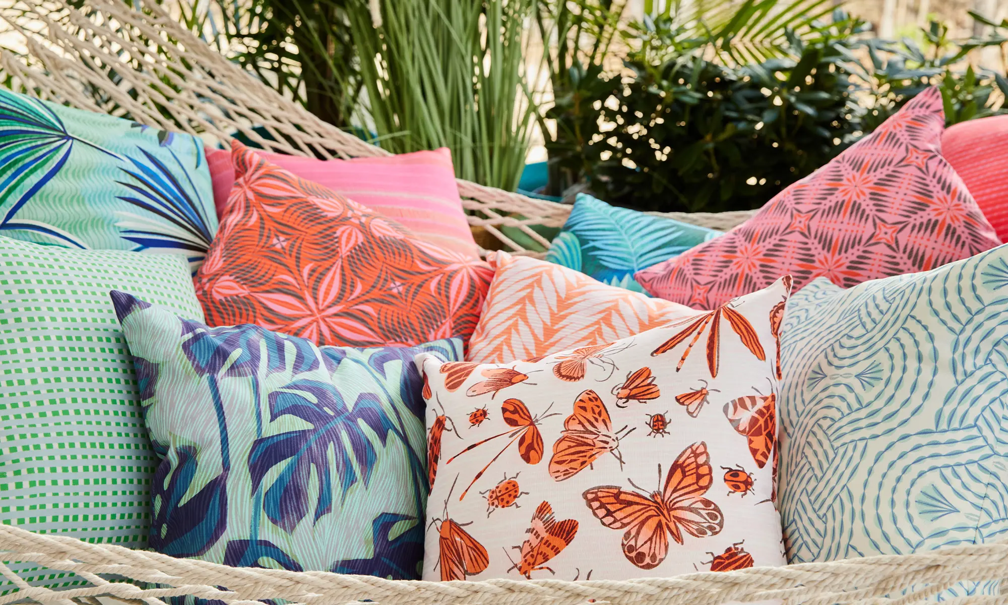 Hammock covered in summery pink and blue outdoor throw pillows.