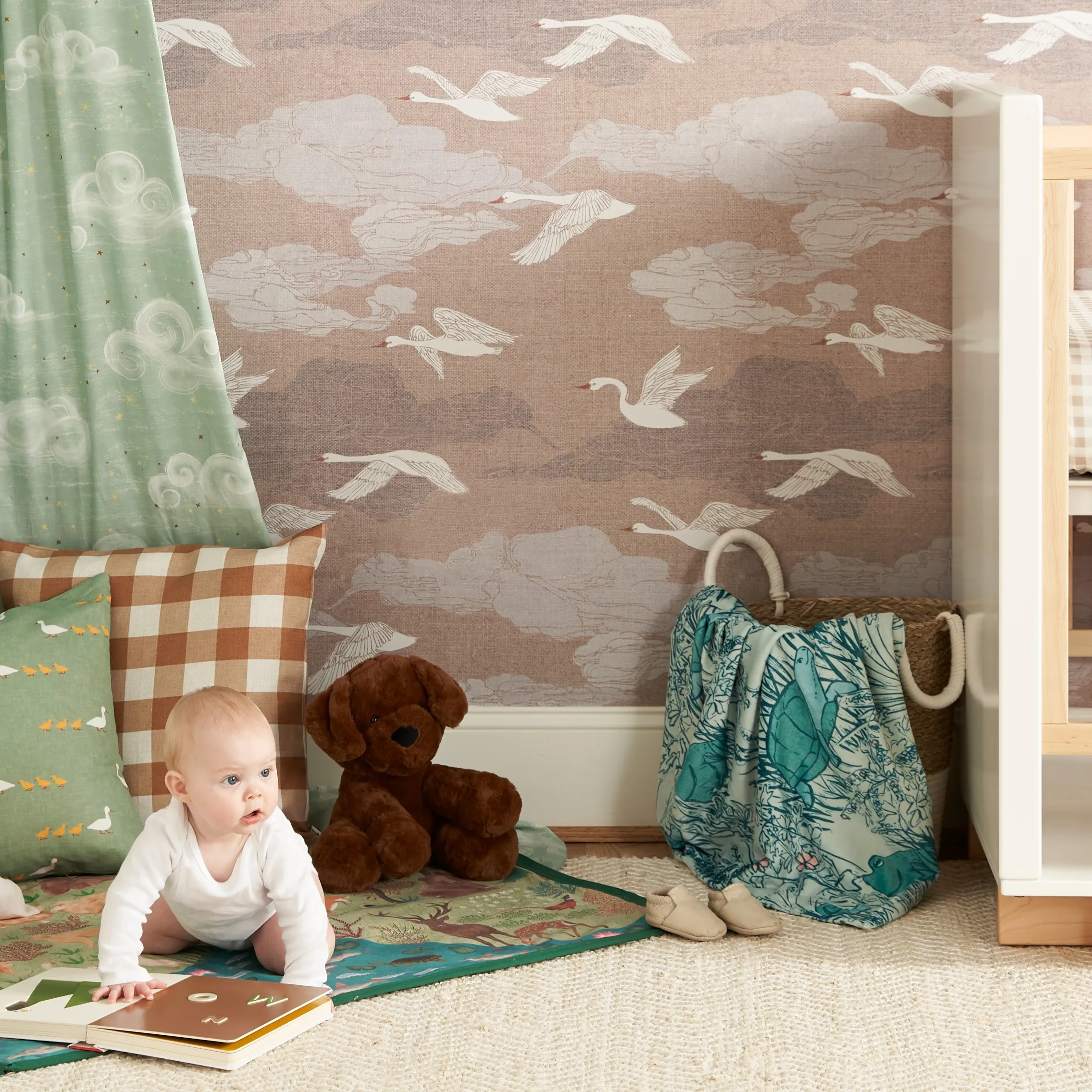 Baby in nursery with swan print wallpaper.