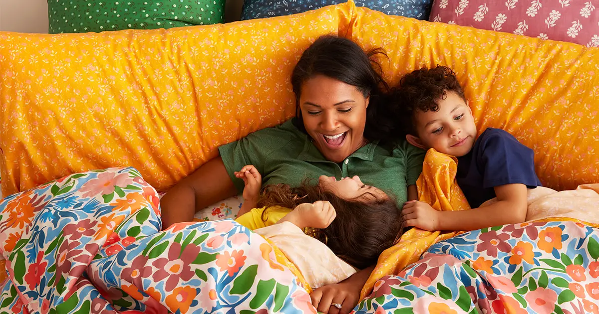 Family in colorful bedding laughing and snuggling