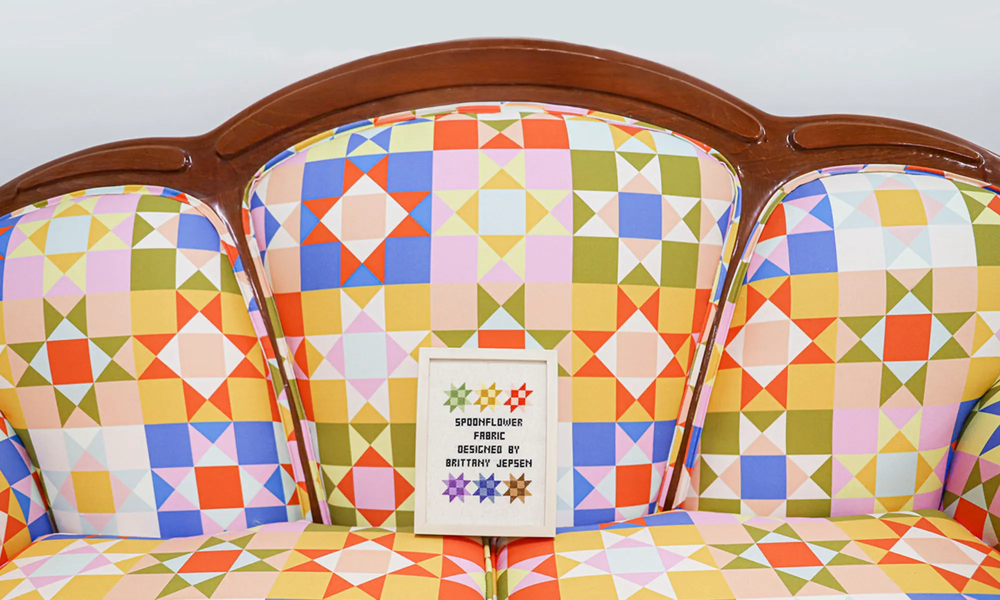 Brightly colored quilt inspired upholstery fabric on a settee.