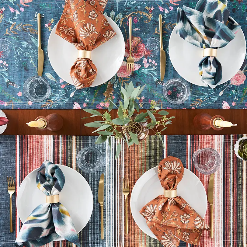 Two southwestern boho table runners and  four napkins on a set dining table.