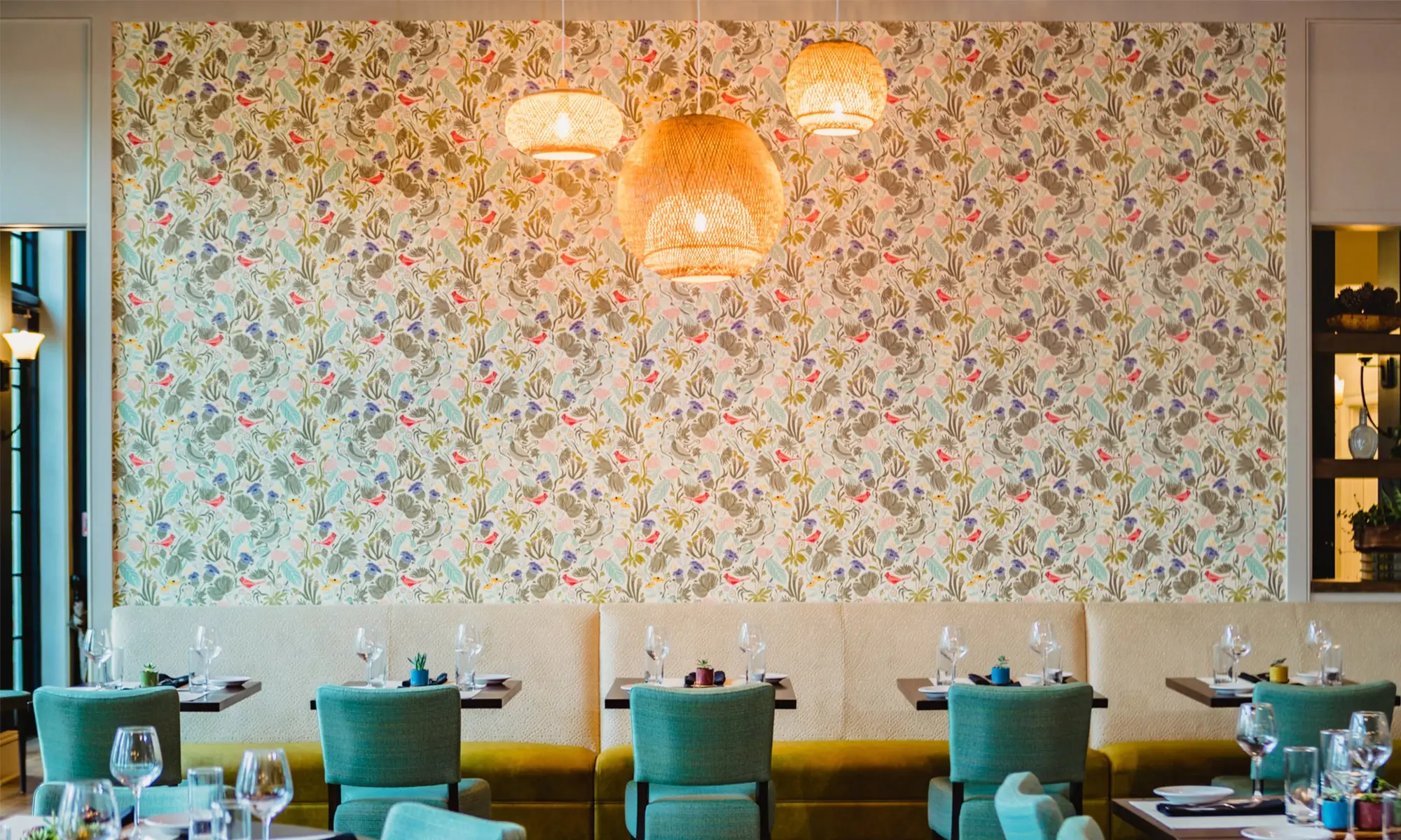 Restaurant with Katie Hayes designed wallpaper on a wall above booths.