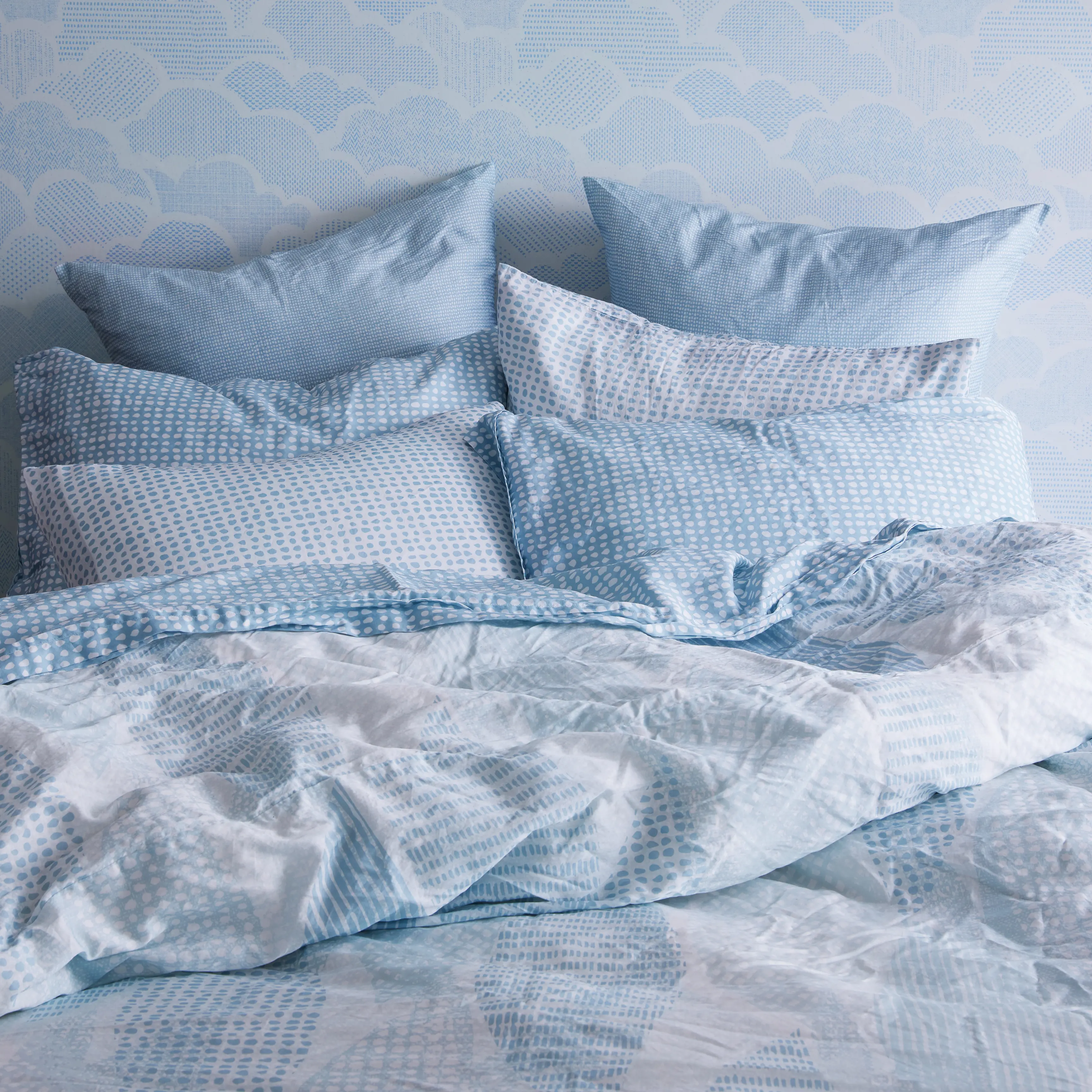 Blue patterned bedding set against matching wallpaper