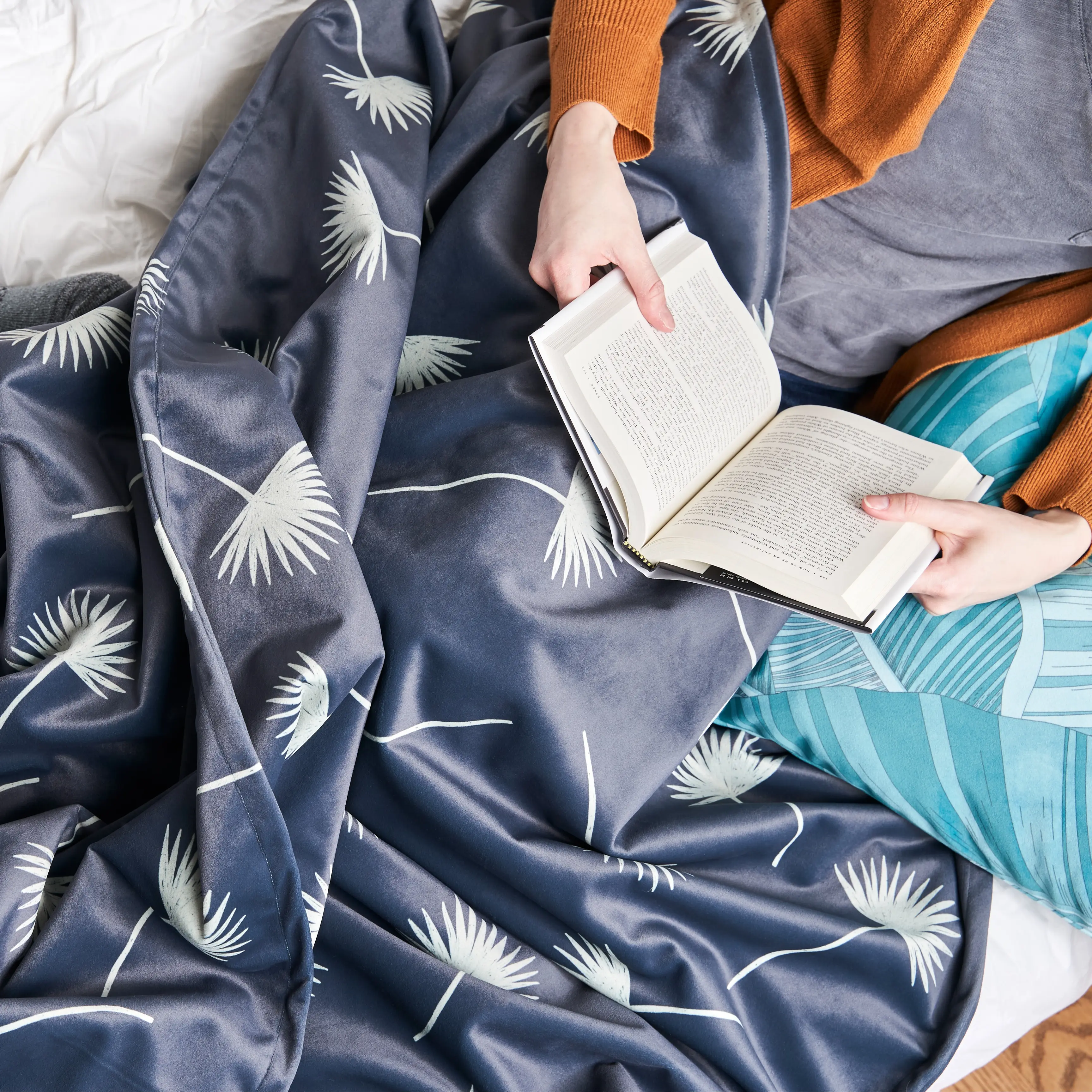 Person reading under a soft throw blanket