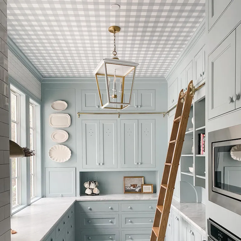 Blue gingham wallpaper on the ceiling of a pale blue kitchen